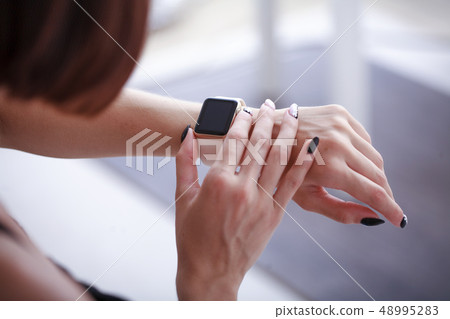 using her smartwatch at home in the living room using her smartwatch at home in the living room 48995283
