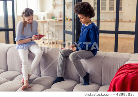 Concentrated boy sitting in semi position on sofa Concentrated boy sitting in semi position on sofa 48995853