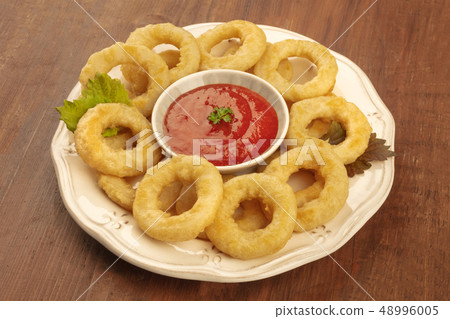 A closeup photo of squid rings with a tomato sauce on a dark wooden background A closeup photo of squid rings with a tomato sauce on a dark wooden background 48996005