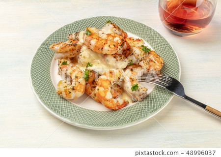 A photo of plate of cooked shrimps on a light background, with a glass of rose wine A photo of plate of cooked shrimps on a light background, with a glass of rose wine 48996037