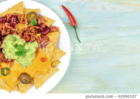 Closeup of nachos with cheese and chilli, traditional Mexican snack, with a pepper and copyspace 48996387
