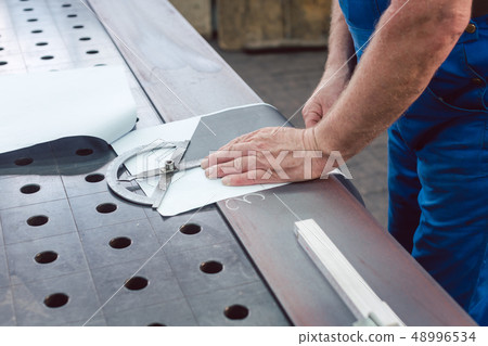 Metalworker with angle meter measuring strip of metal Metalworker with angle meter measuring strip of metal 48996534