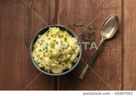 Pomme puree, an overhead photo of a bowl of mashed potatoes with herbs, shot from the top on a Pomme puree, an overhead photo of a bowl of mashed potatoes with herbs, shot from the top on a 48997083