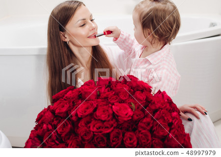 Beautiful mother posing with girl and big bouquet Beautiful mother posing with girl and big bouquet 48997979
