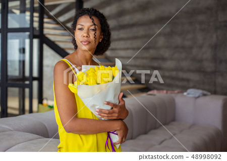 Attractive international female person embracing her flowers 48998092