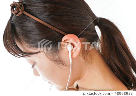 Young woman listening to music on earphones 48998982