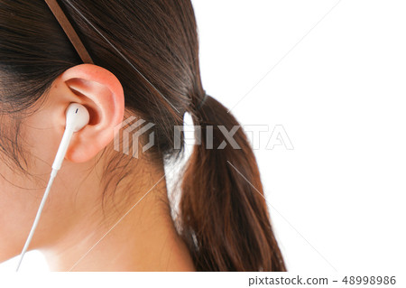 Young woman listening to music on earphones 48998986