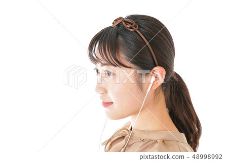 Young woman listening to music on earphones 48998992