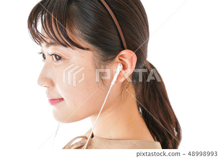 Young woman listening to music on earphones 48998993