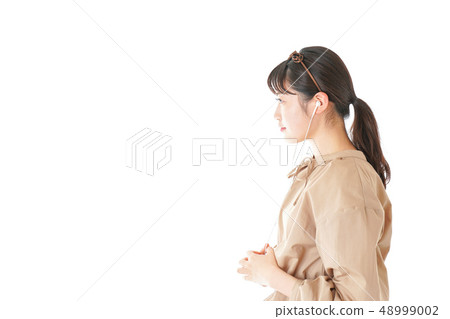 Young woman listening to music on earphones 48999002