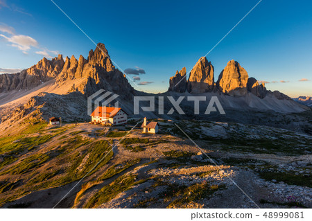 Tre Cime and rifugio hut at sunrise in Dolomite Tre Cime and rifugio hut at sunrise in Dolomite 48999081
