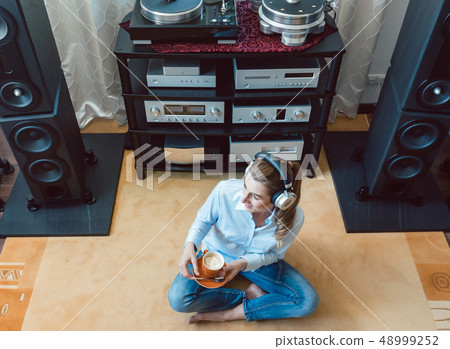 Woman listening to music from a Hi-Fi stereo Woman listening to music from a Hi-Fi stereo 48999252