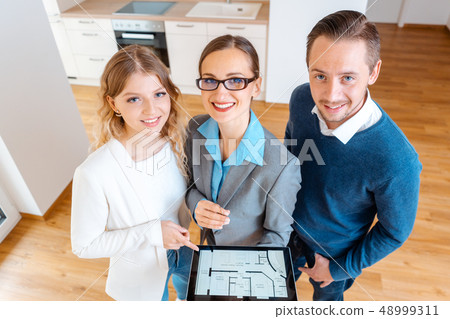 House broker and clients in new apartment looking into camera House broker and clients in new apartment looking into camera 48999311