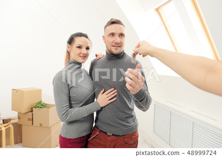 The seller gives customers the keys to the new apartment. The seller gives customers the keys to the new apartment. 48999724