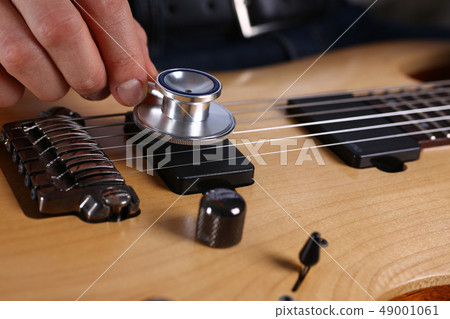 Male arms hold stethoscope head diagnosing guitar Male arms hold stethoscope head diagnosing guitar 49001061