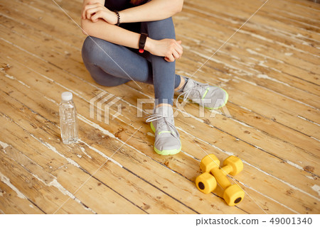 Sport young female at gym taking a break from workout and dumbbell were placed nearby. 49001340