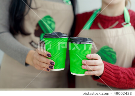 two barista in aprons is holding hot coffee in two barista in aprons is holding hot coffee in 49002428