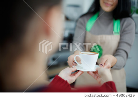 Barista in apron in coffee shop give just brewed Barista in apron in coffee shop give just brewed 49002429
