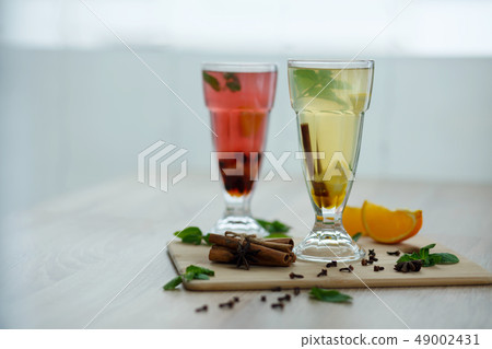 two glasses with colored hot drinks from which 49002431