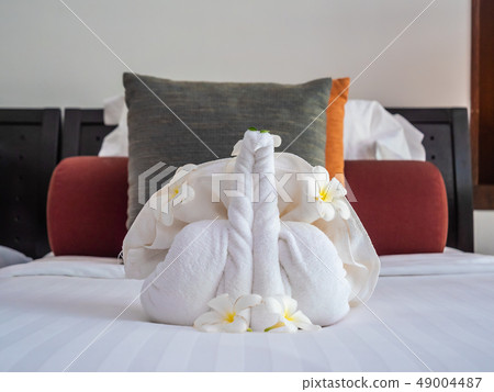 White elephant towel and comfortable pillow on bed 49004487