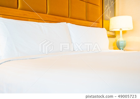 White comfortable pillow on bed with table light lamp decoration in hotel bedroom 49005723