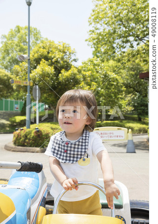 Toddler riding a battery car at an amusement park 49008119