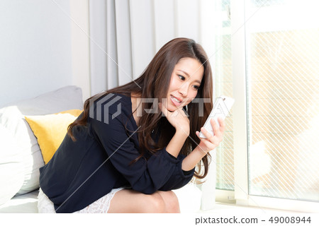 A woman watching a smartphone 49008944