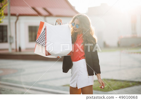 Positive woman walking at street after shopping 49010068
