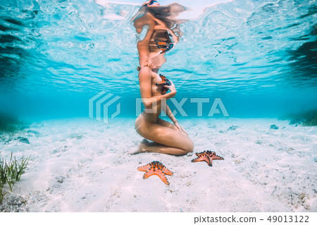 Nude woman swimming with starfish, underwater Nude woman swimming with starfish, underwater 49013122