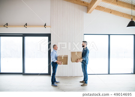 Two men holding cardboard boxes in front of them when furnishing new house. 49014695