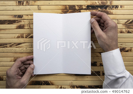 Mens hands holding white booklet Mens hands holding white booklet 49014762