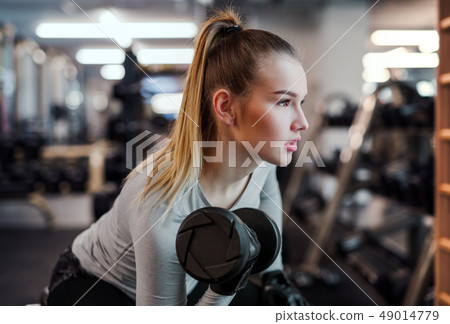 Young girl or woman with dumbbells, doing workout in a gym. 49014779