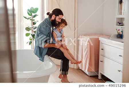 A small girl with young father in bathroom at home, looking at painted nails. A small girl with young father in bathroom at home, looking at painted nails. 49015296