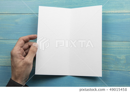 Mens hand holding white booklet 49015458