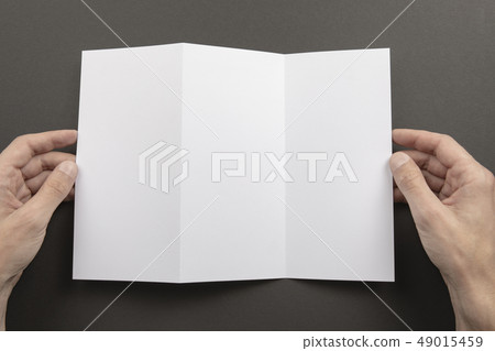 Mens hands holding white booklet Mens hands holding white booklet 49015459
