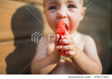 Close-up of small girl outdoors in summer, eating watermelon. Close-up of small girl outdoors in summer, eating watermelon. 49015461