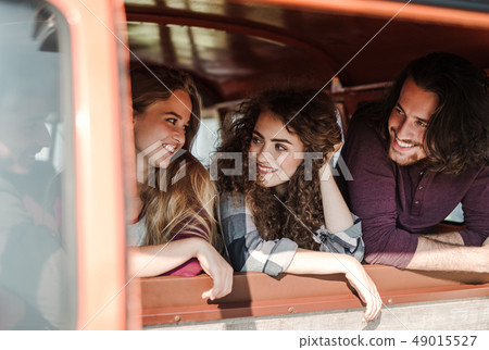 A group of young friends on a roadtrip through countryside, looking out of window. 49015527
