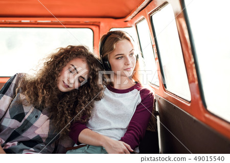 Young female friends on a roadtrip through countryside, sitting in minivan. 49015540
