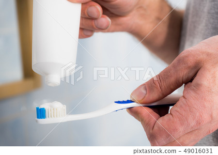 Person putting toothpaste on toothbrush 49016031