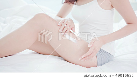 Woman apply sunscreen onto her leg 49016655