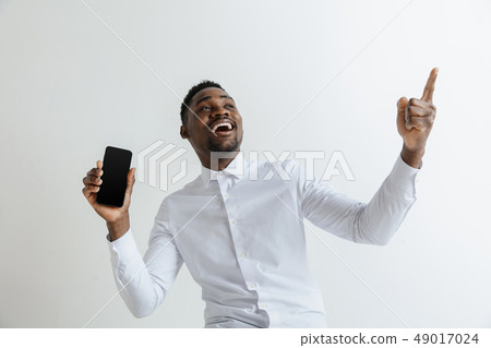 Indoor portrait of attractive young black african man isolated on pink background, holding blank Indoor portrait of attractive young black african man isolated on pink background, holding blank 49017024