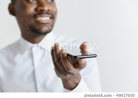 Indoor portrait of attractive young black african man isolated on gray background, holding blank Indoor portrait of attractive young black african man isolated on gray background, holding blank 49017030