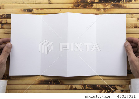 Mens hands holding white booklet 49017031