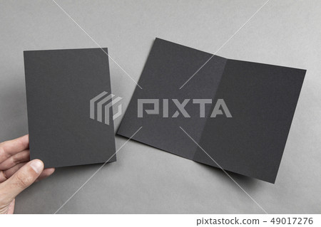 Mens hand holding black booklet Mens hand holding black booklet 49017276