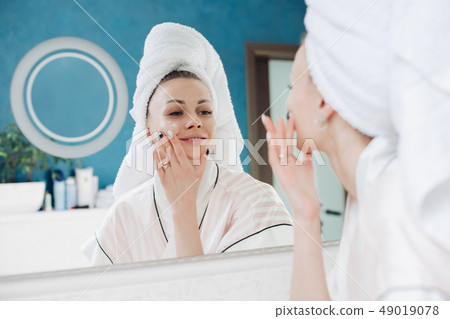 Young lady standing in light bathroom after Young lady standing in light bathroom after 49019078