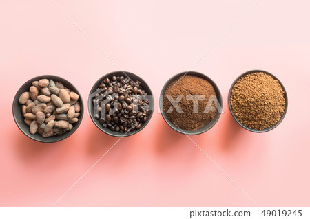 Concept of cocoa and coffee beans in bowls on pink Concept of cocoa and coffee beans in bowls on pink 49019245