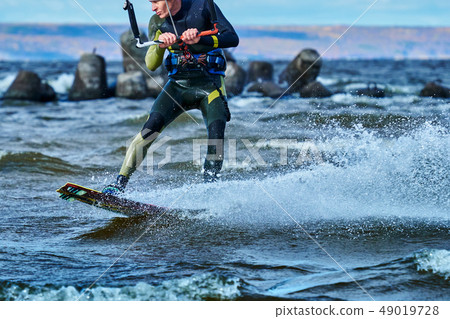 A male kiter slides on the surface of the water. A male kiter slides on the surface of the water. 49019728