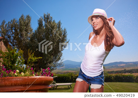 Happy sexy woman watering flowers in italy garden 49020419