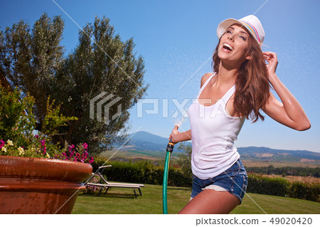 Happy sexy woman watering flowers in italy garden 49020420
