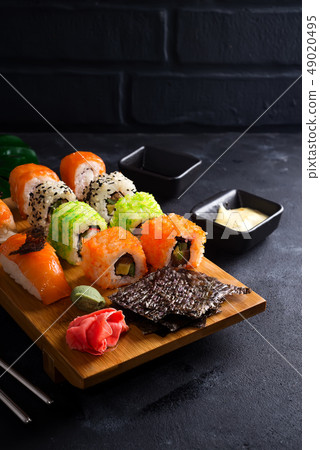 Asian food background with black iron teapot and sushi set on wooden plate on black stone table 49020495